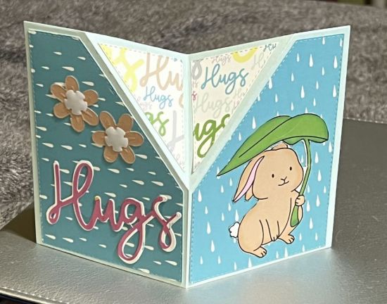 Hugs
February card kit. Bunny under a leaf in the rain. The word �Hugs� on the other flap. 
