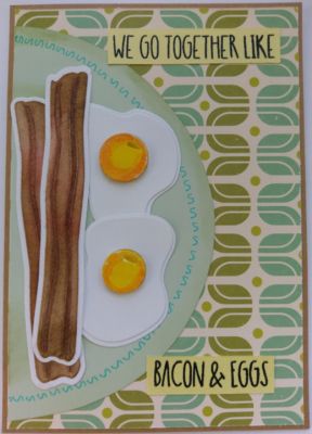 Putting the bacon and eggs on a plate is one way to place them on your card front
The bacon and eggs are placed on a circular plate, using a background pattern paper as a tablecloth. The plate can go on either side with this design. It's edges were distressed inked and a small squiggly pattern was drawn around the outer edge. With just a small effort of adding color to these cutting dies, you can have realistic looking bacon & eggs. Plus the sentiments included in this set have so many possibilities.  
Keywords: bacon eggs