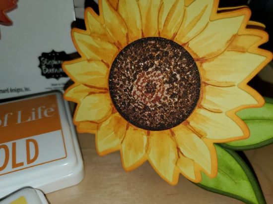 Sunflower Birthday Card Close-up
Center of the sunflower was created by dotting brown copics E77, E27 an E25 on gold glitter paper.  Sunflower and marigold ink were watercolored on top of banana cardstock for the petals with light strokes of copic YR27 at the base of and between petals.  
Keywords: sunflower, fold-it, birthday
